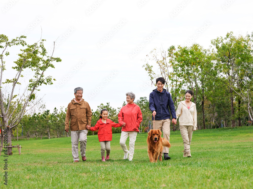 Happy family of five and pet dog walking in the park