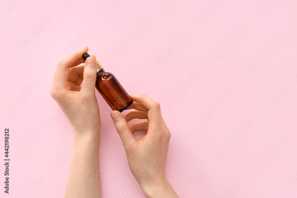 Woman holding bottle of essential oil on color background