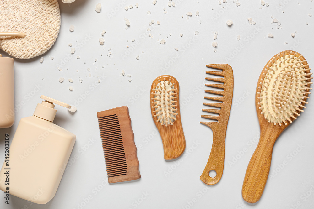 Hair brushes, combs and bath supplies on light background