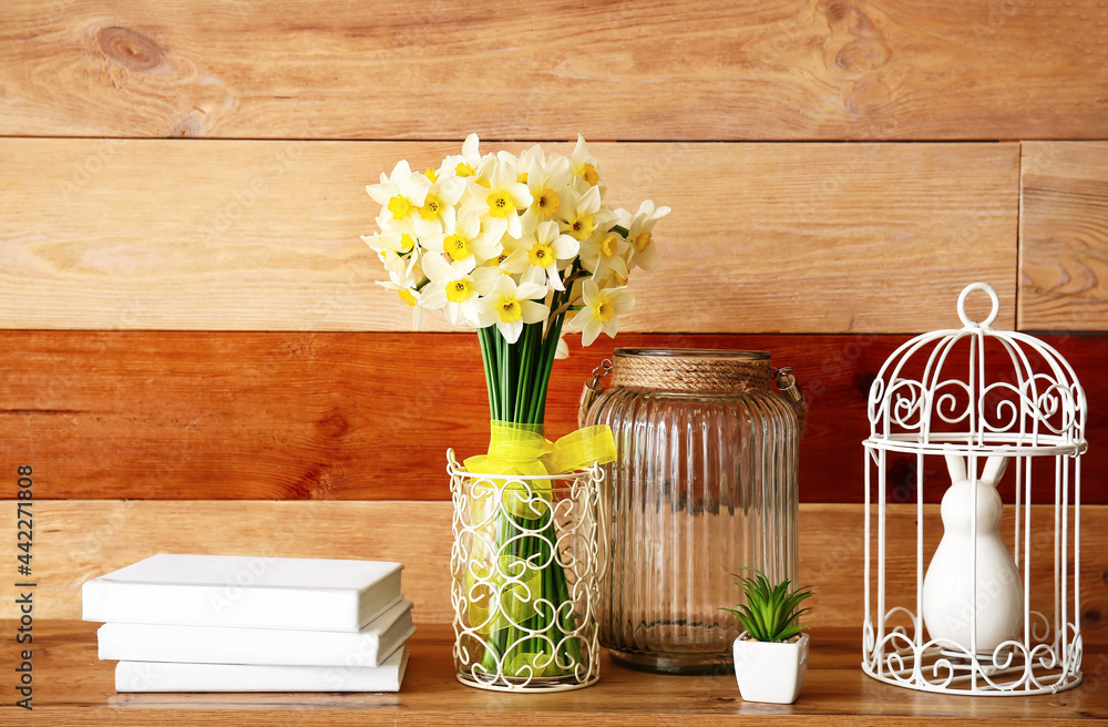 Vase with narcissus flowers, decor and books on table