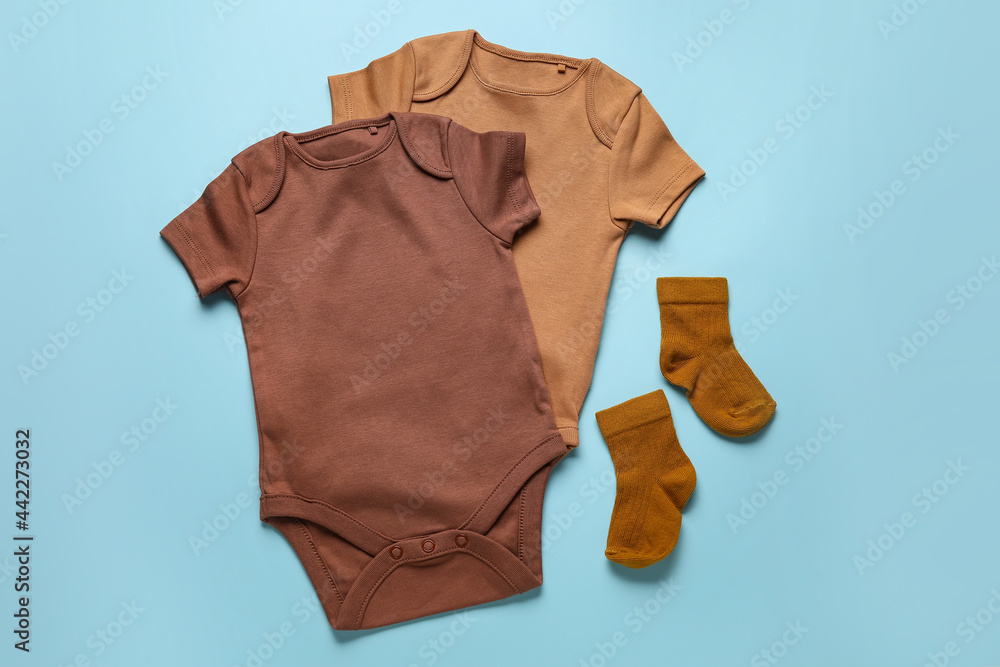 Baby clothes and socks on color background