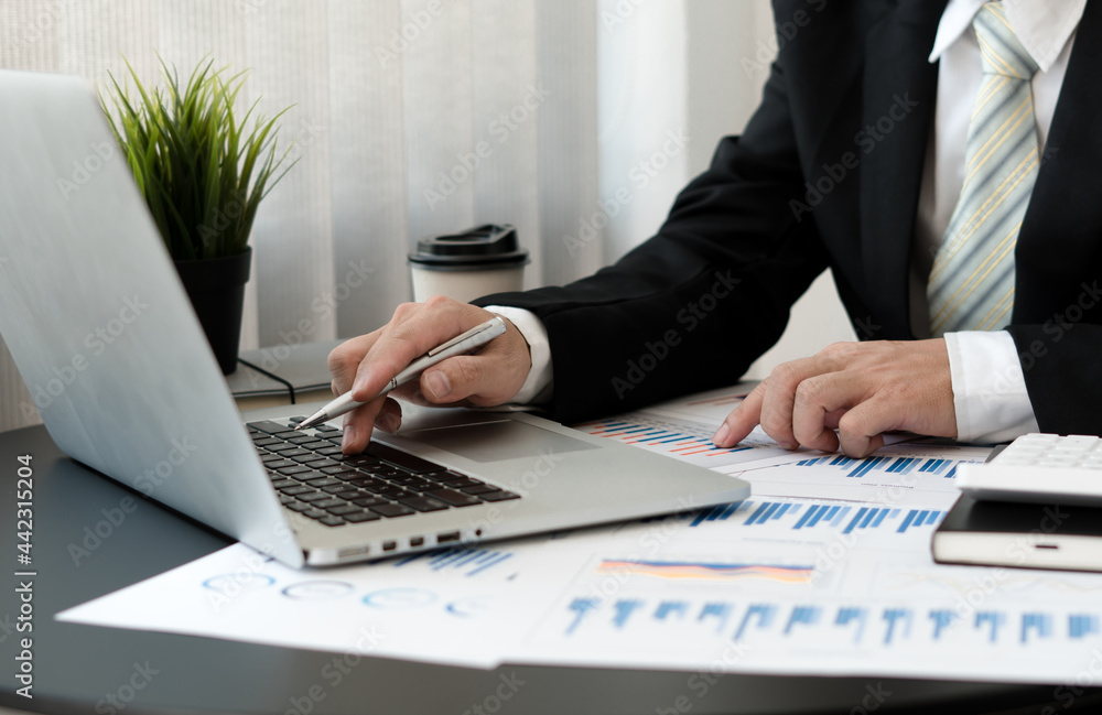 businessman hand working on laptop computer with financial business graph information, analyzing inv