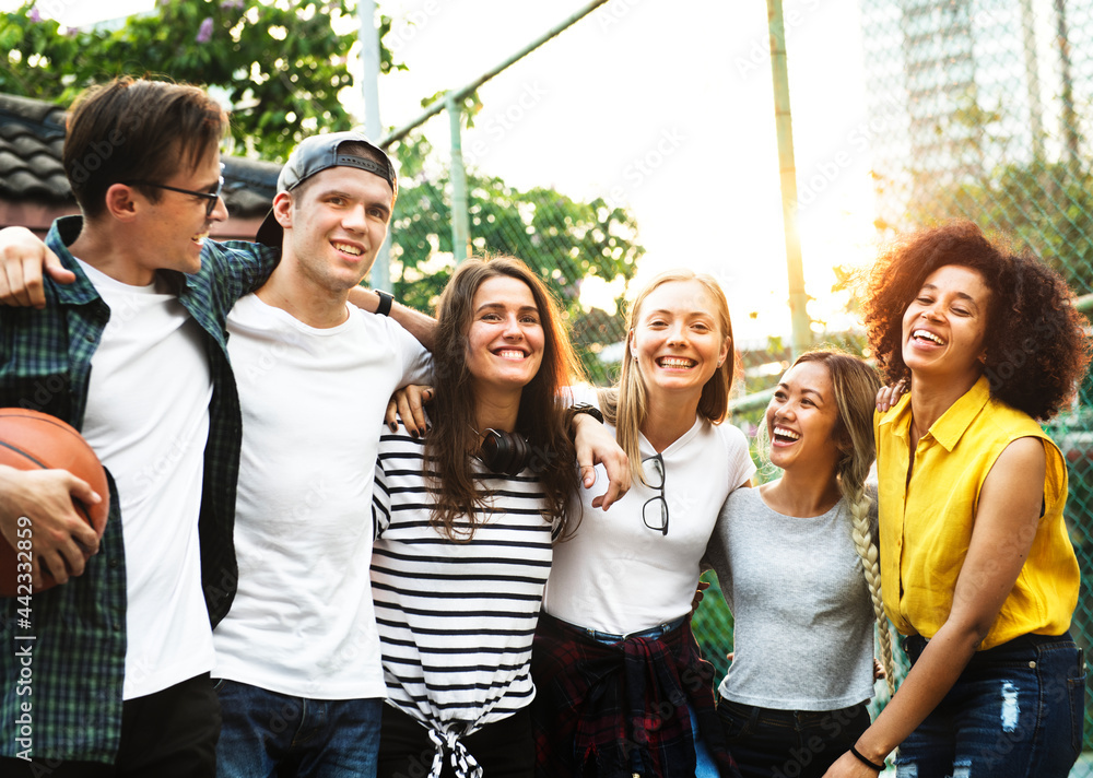 Smiling happy young adult friends arms around shoulder outdoors friendship and connection concept