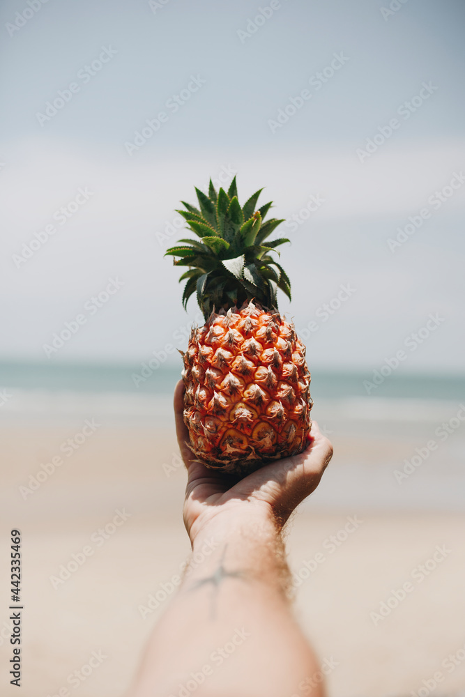 Man holding a pineapple at the beach