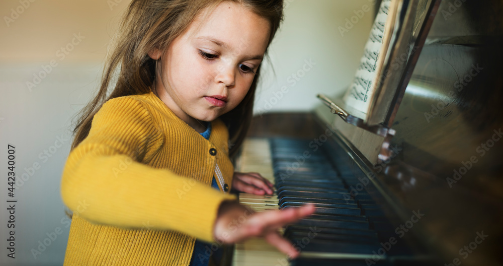 Cute and adorable little girl learning how to play a piano