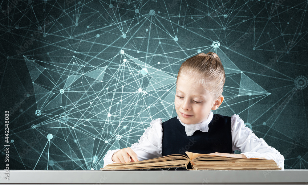 Smiling little girl sitting at desk with open book