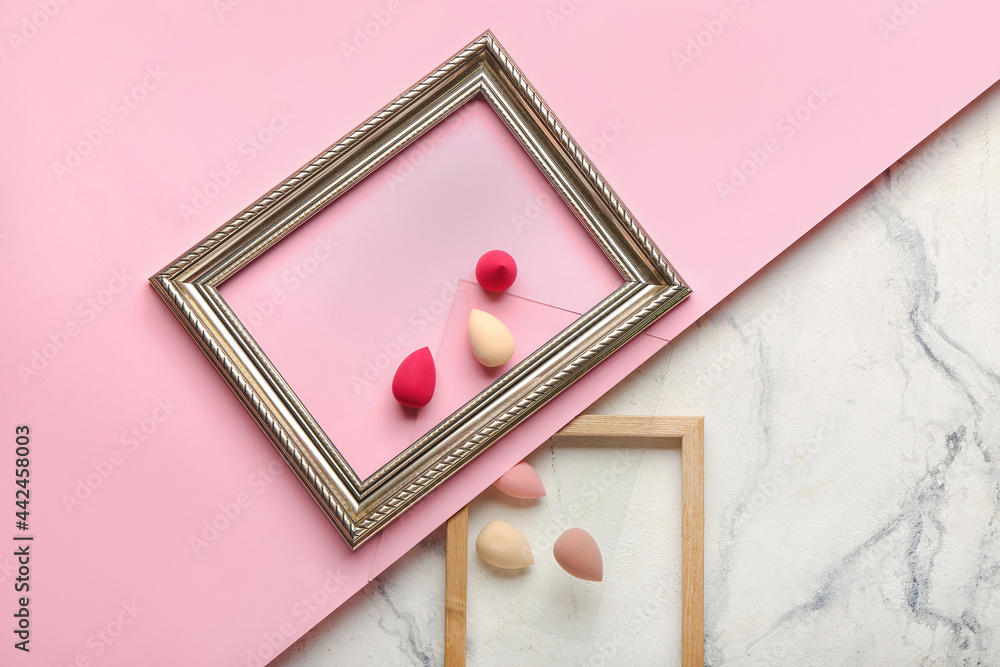 Makeup sponges and frames on color background