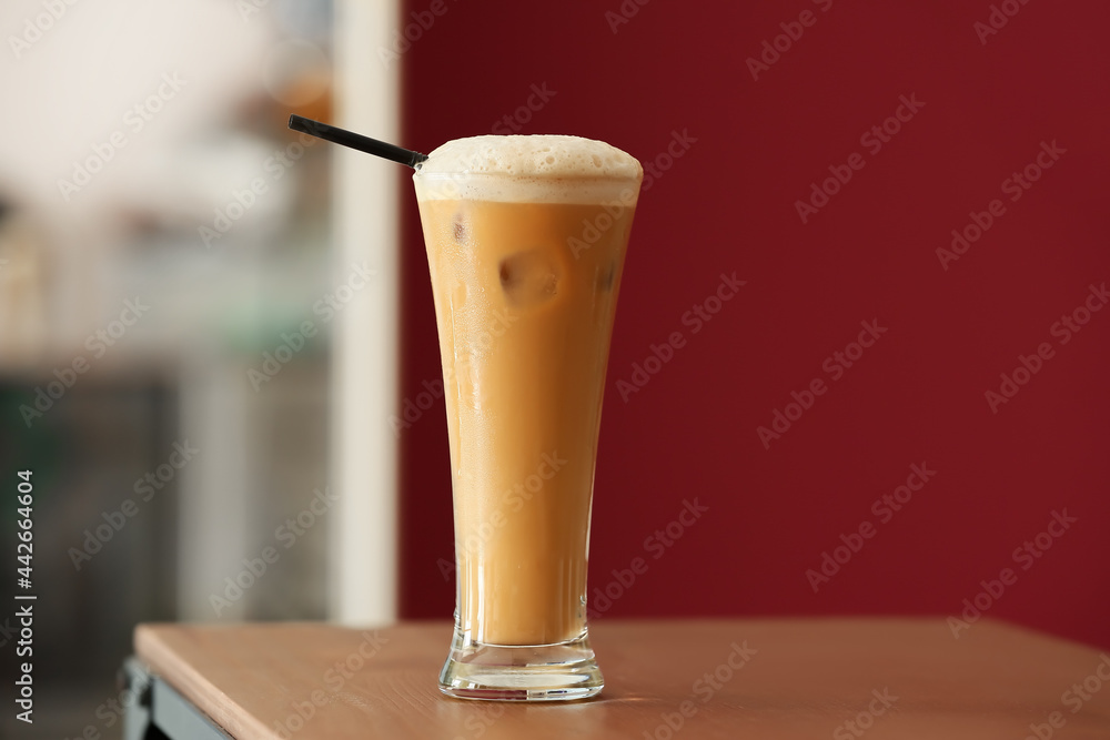 Glass of tasty iced coffee with milk on table