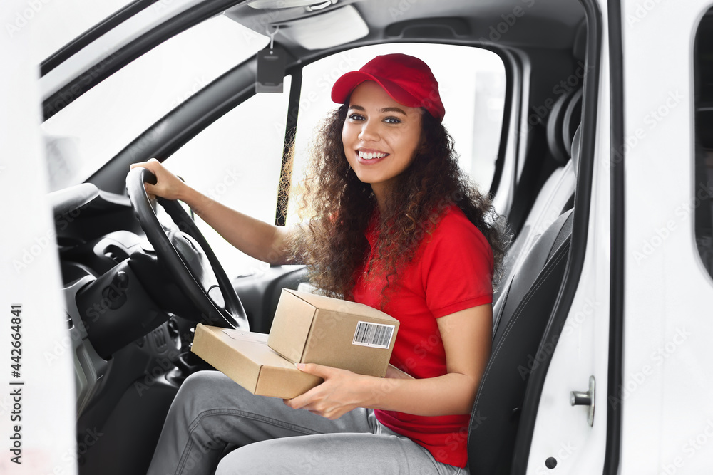 African-American courier of delivery company sitting in car