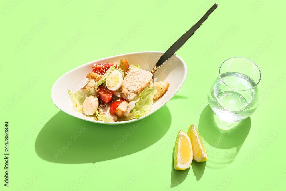 Bowl with Caesar salad on color background