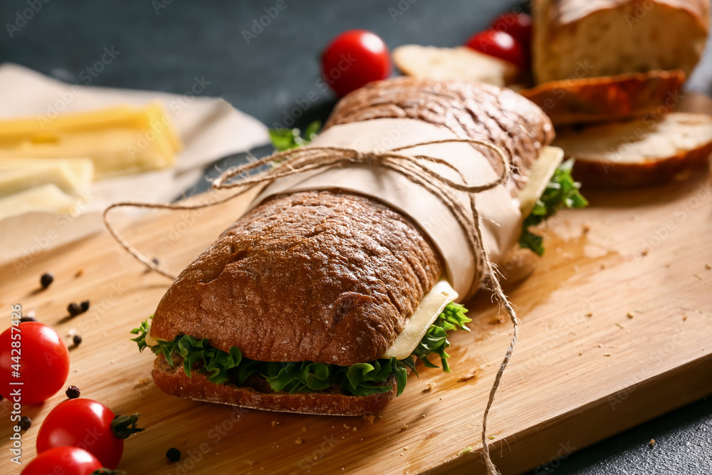 Board with tasty sandwich on dark background, closeup