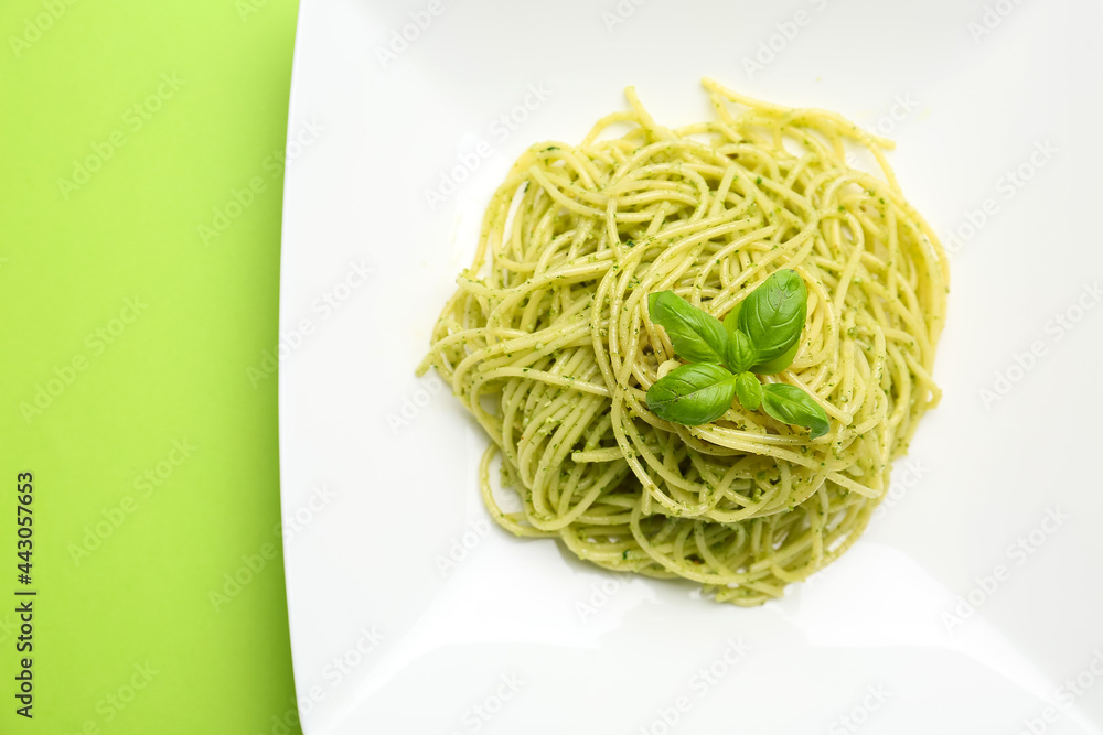 Plate with tasty pesto pasta on color background