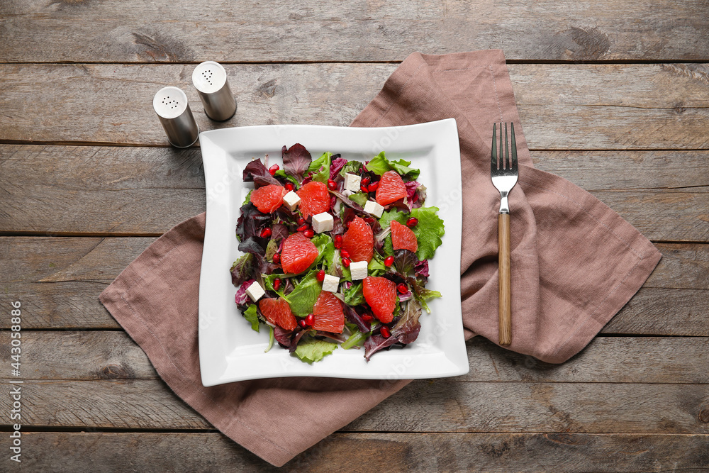 Plate with tasty grapefruit salad on wooden table