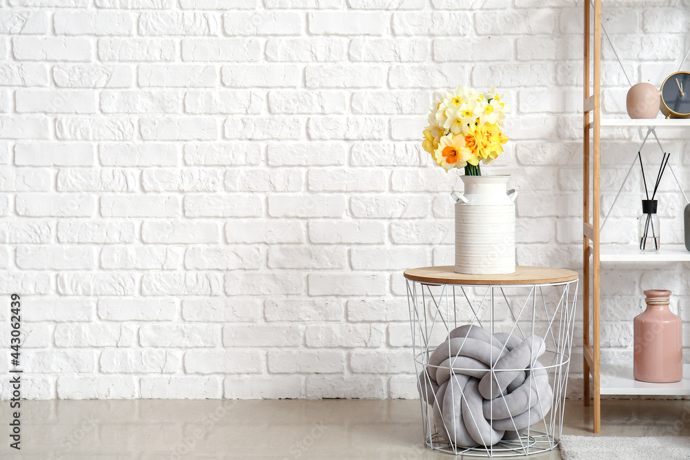 Vase with narcissus flowers on table in room