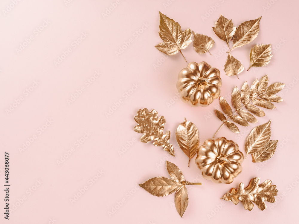 Gold autumn leaves on pink background. Autumn concept. Top view of autumn leaves in gold paint on wh