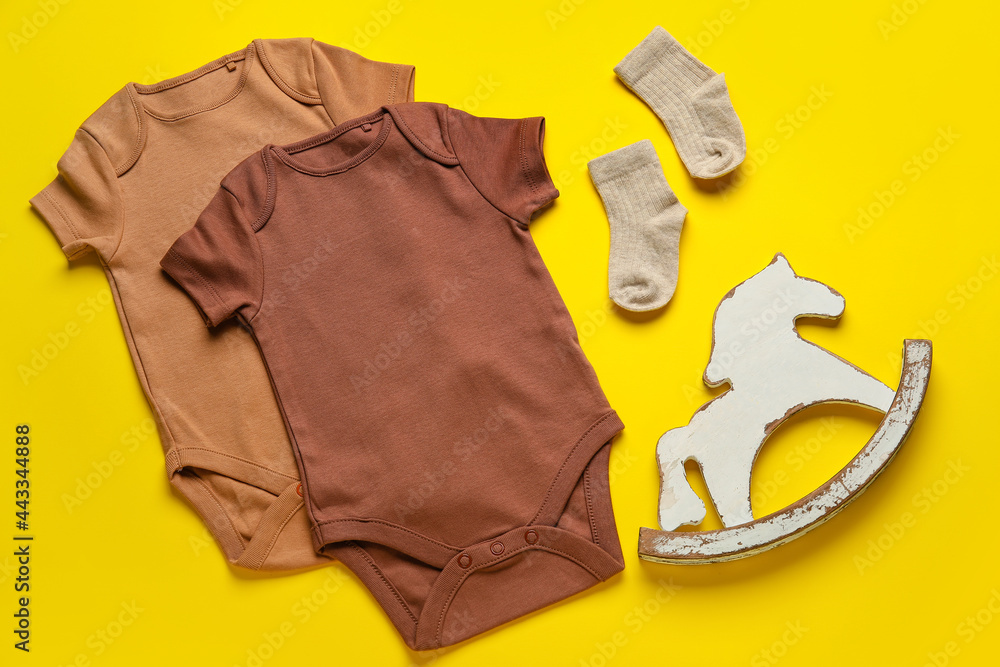 Baby clothes, socks and toy on color background