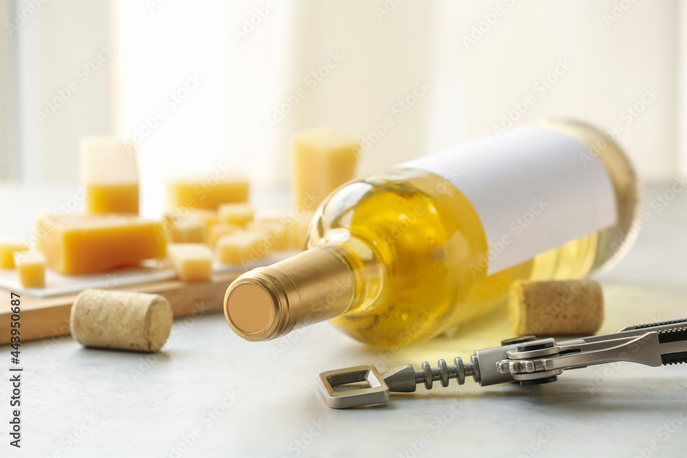 Wooden board with bottle of exquisite wine and corkscrew on light table