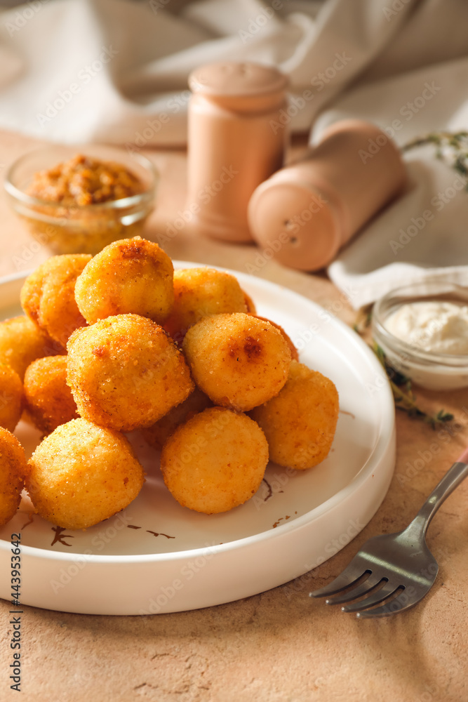 Plate with fried potato balls on color background