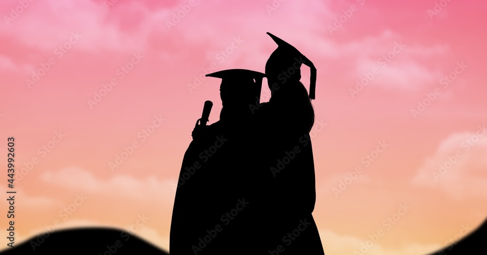 Composition of silhouettes of two graduated students in caps and gowns against sunset sky