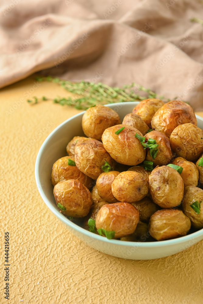 Bowl with tasty baked potato on color background