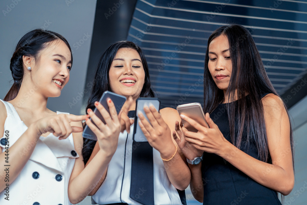 Three women friends having conversation while looking at mobile phone in their hands. Concept of soc