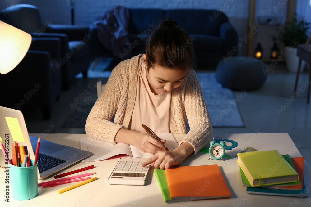 Little girl doing homework at home late in evening