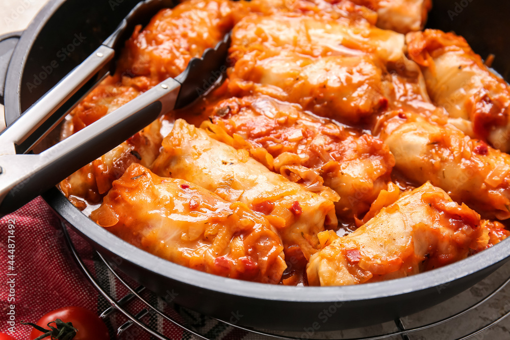 Frying pan with tasty stuffed cabbage rolls on light background