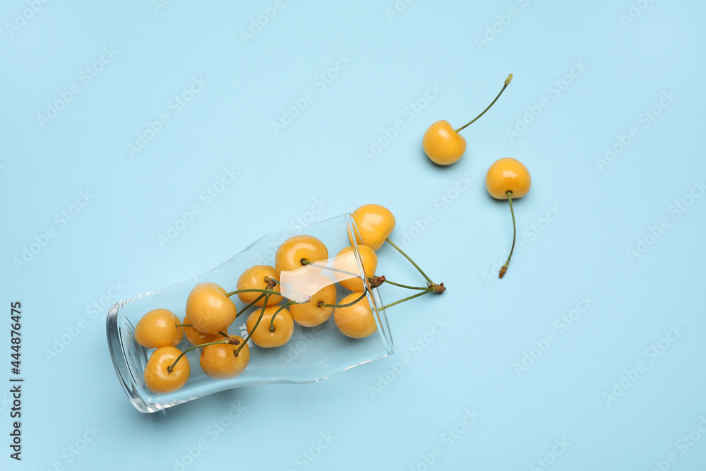 Glass with tasty sweet cherries on color background