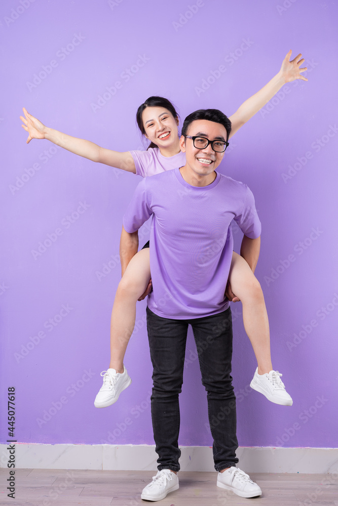 Young Asian couple posing on purple background