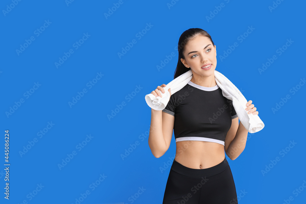 Sporty female coach with towel on color background