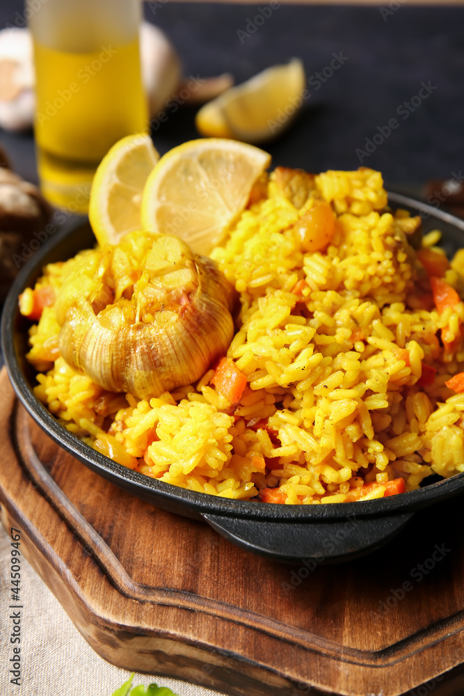 Frying pan with tasty pilaf on table