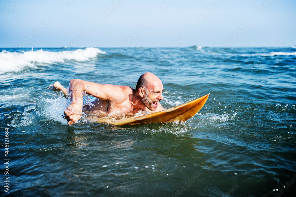 A senior man on a surfboard