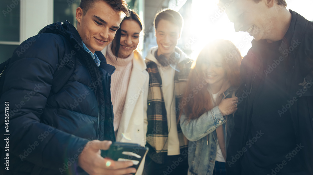 Young man showing mobile phone to his friends