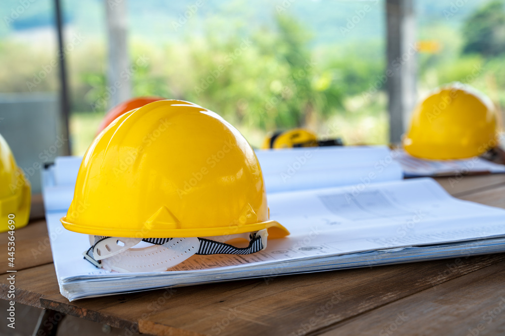 Hard hat construction plans and the blueprint at construction site.