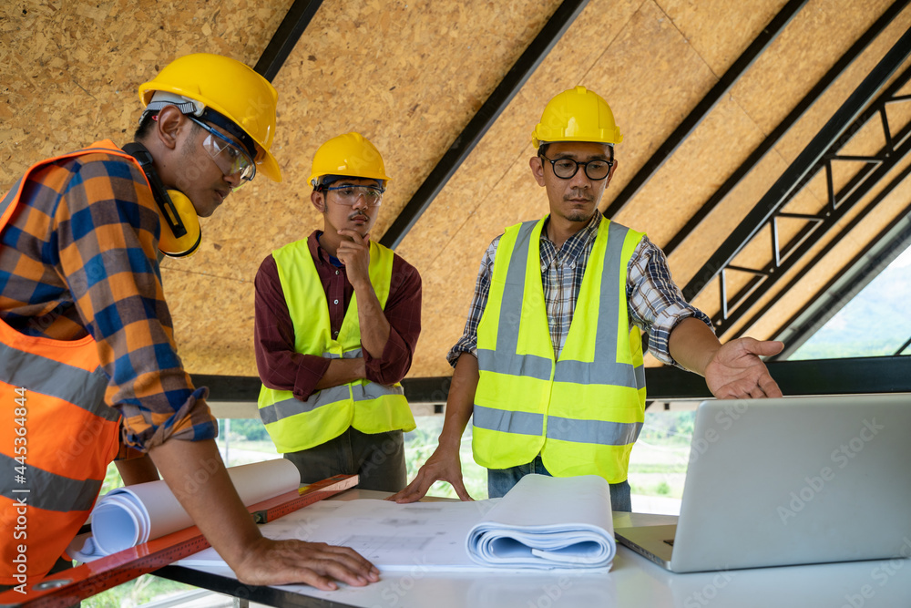 Engineers or architect holding a pen with drawings in construction on blueprints in construction sit