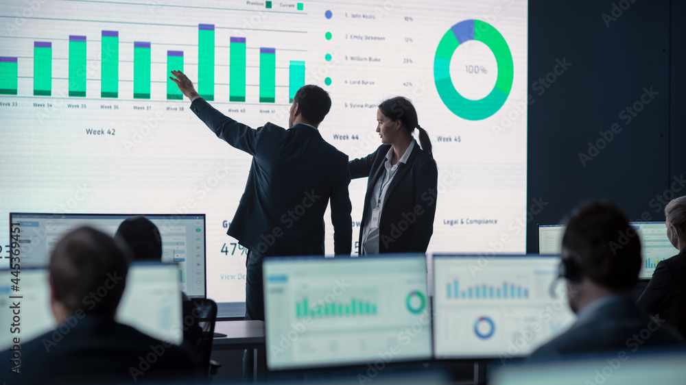 Two Traders Having a Meeting in a Modern Monitoring Office with Analytics Feed on a Big Digital Scre