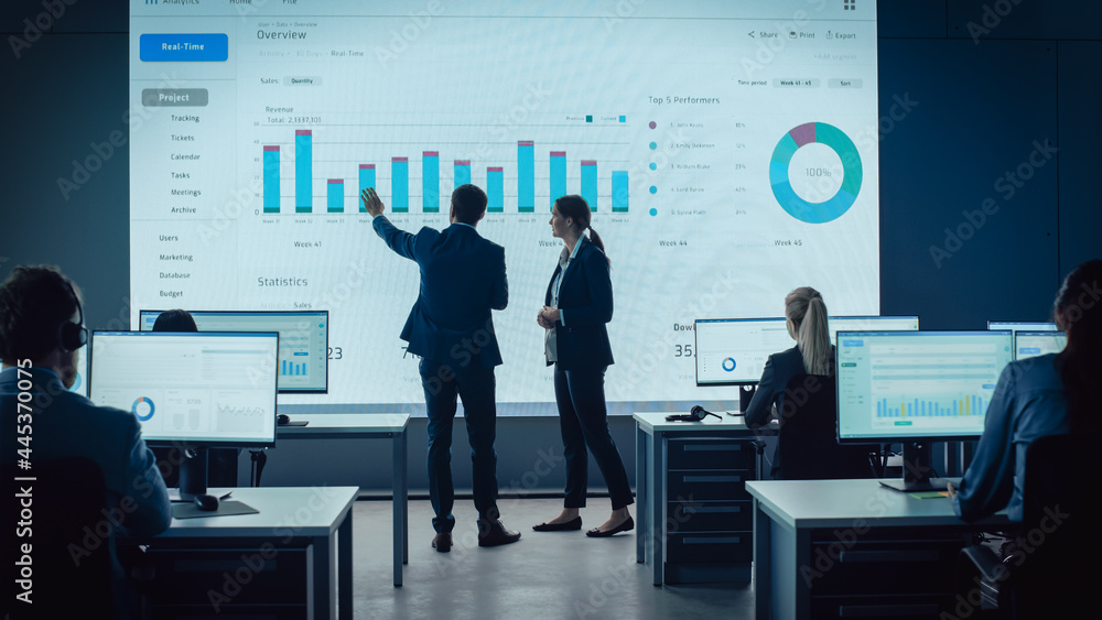 Two Traders Having a Meeting in a Modern Monitoring Office with Analytics Feed on a Big Digital Scre