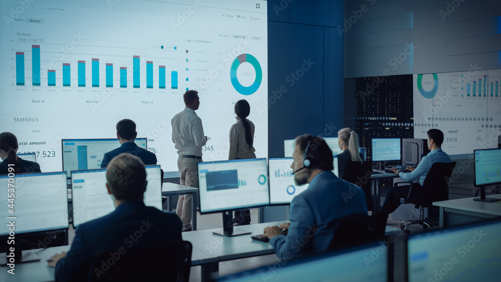 Two Traders Having a Meeting in a Modern Monitoring Office with Analytics Feed on a Big Digital Scre