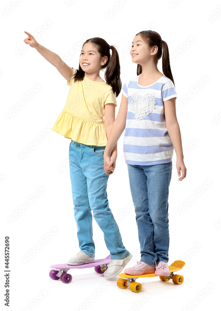 Cute Asian sisters with skateboards on white background