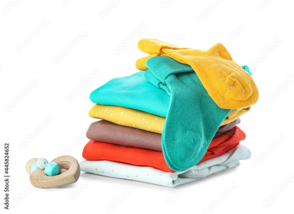 Stack of baby clothes and teether on white background