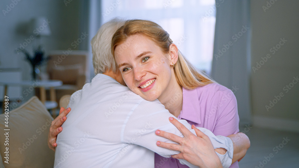 Hugging elderly mother and smiling daughter in the apartment