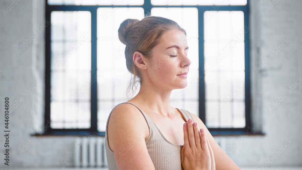 穿着米色运动服闭着眼睛的漂亮女人在namaste mudra深呼吸