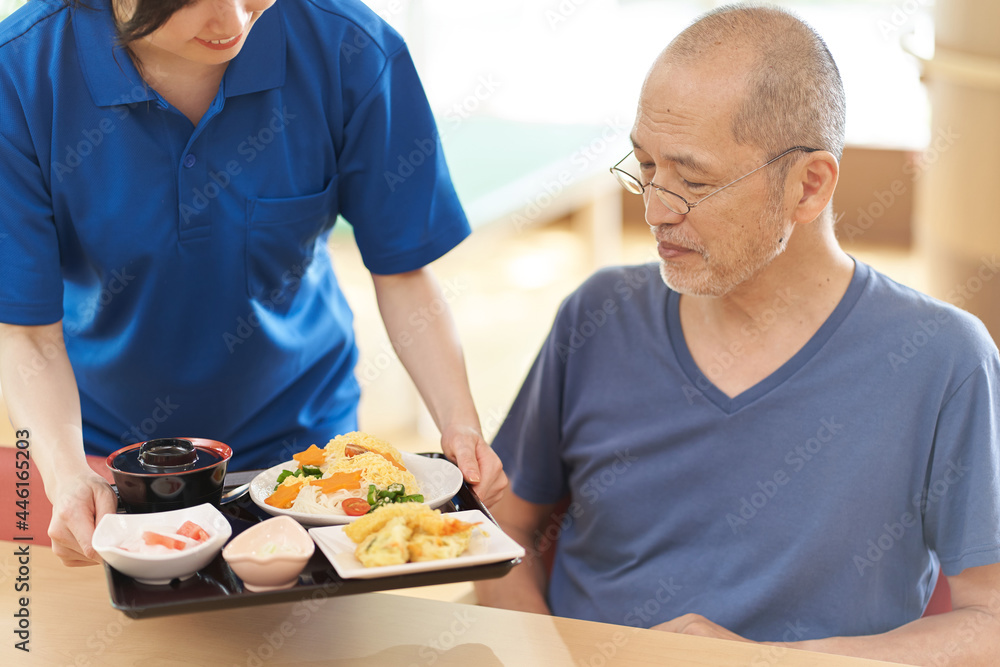 高齢者に配膳をする介護士