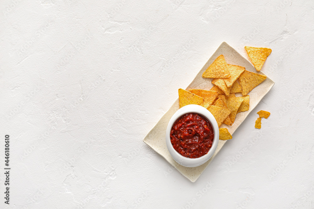 Bowl of tasty salsa sauce and nachos on white background