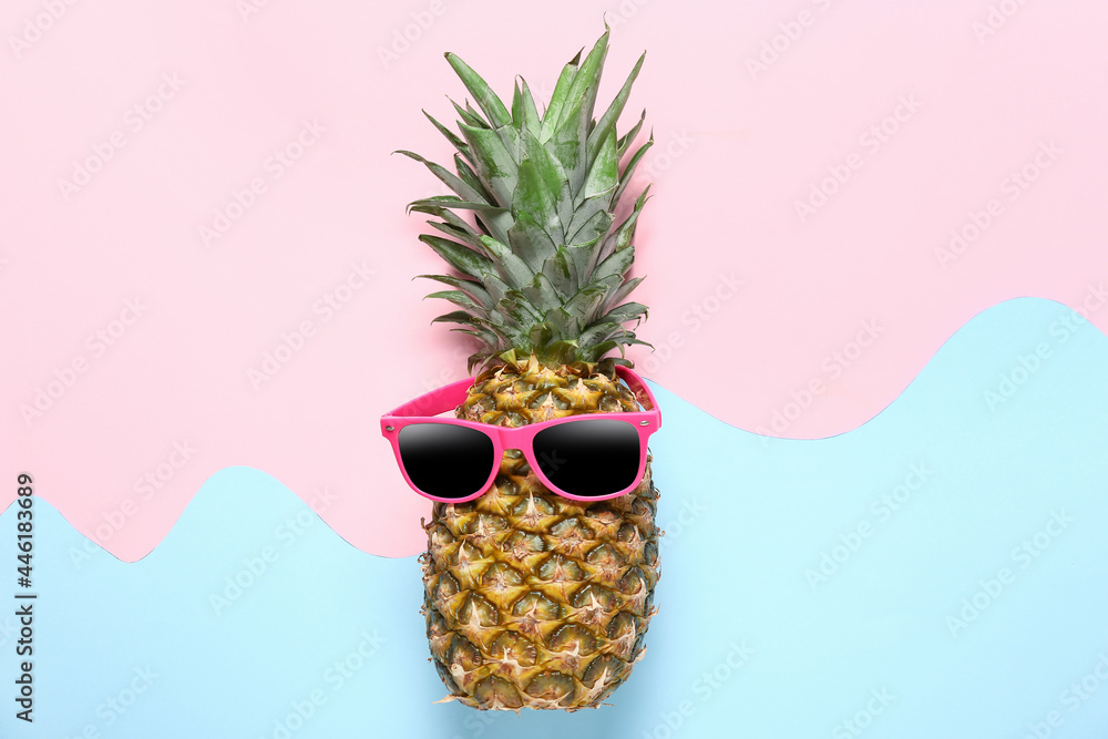 Funny pineapple in sunglasses on color background