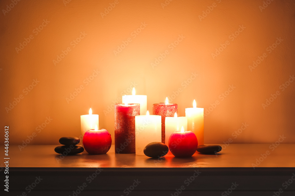 Burning candles and spa stones on shelf in dark room