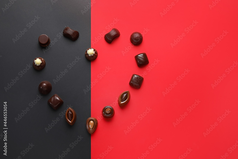 Heart made of sweet chocolate candies on color background