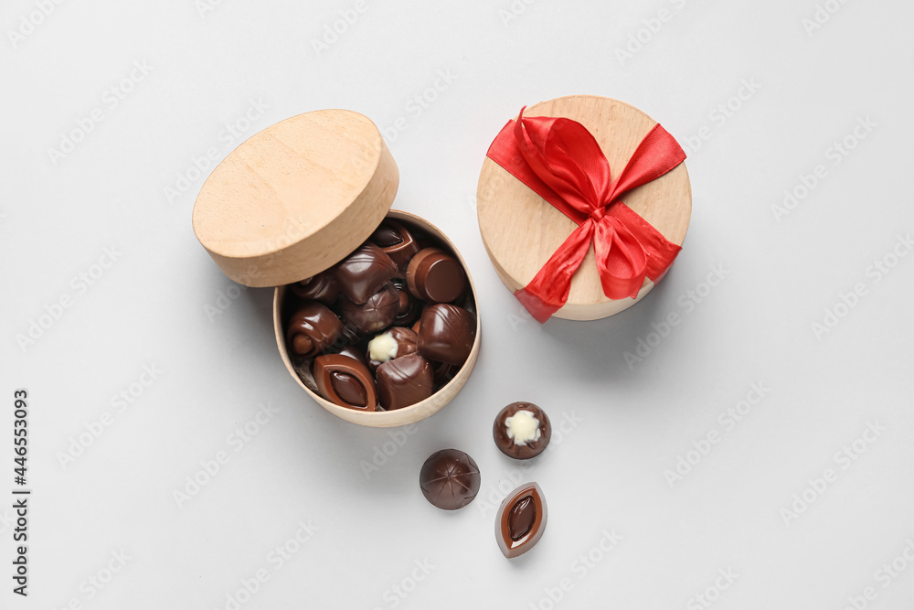 Box with sweet chocolate candies on light background