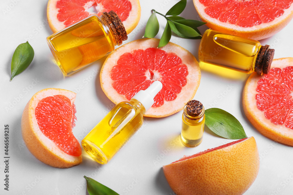 Composition with bottles of essential oil and grapefruit slices on light background