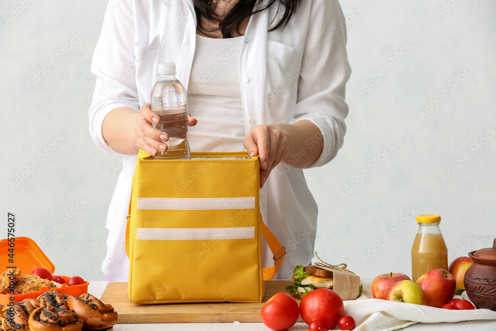 女人在厨房把一瓶水装进饭盒袋